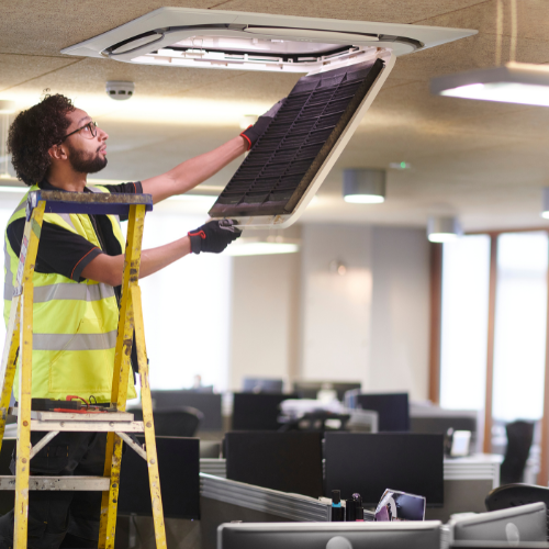 A man working on an AC vent in an office