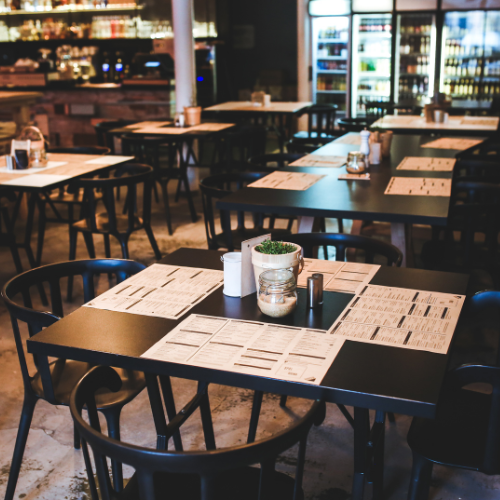 Empty restaurant tables and chairs arranged neatly, waiting for guests to arrive and enjoy a meal.